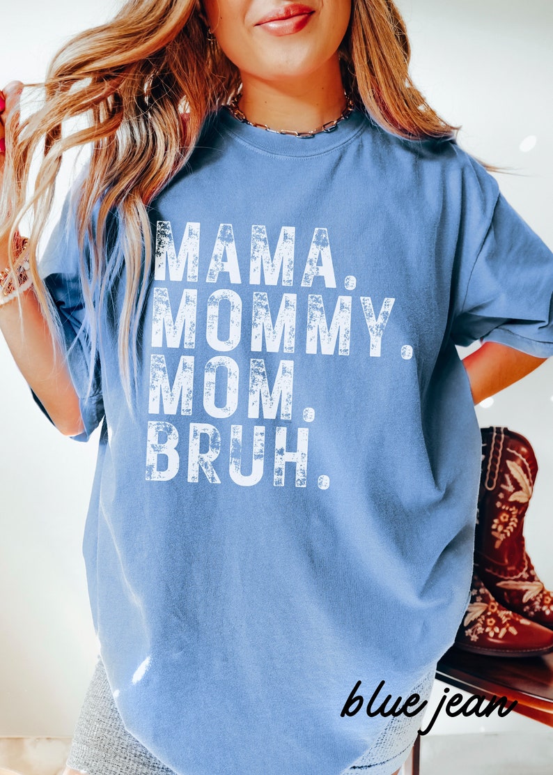 May include: A blue t-shirt with the text "MAMA. MOMMY. MOM. BRUH." printed in white on the front. The text has a distressed, vintage look.