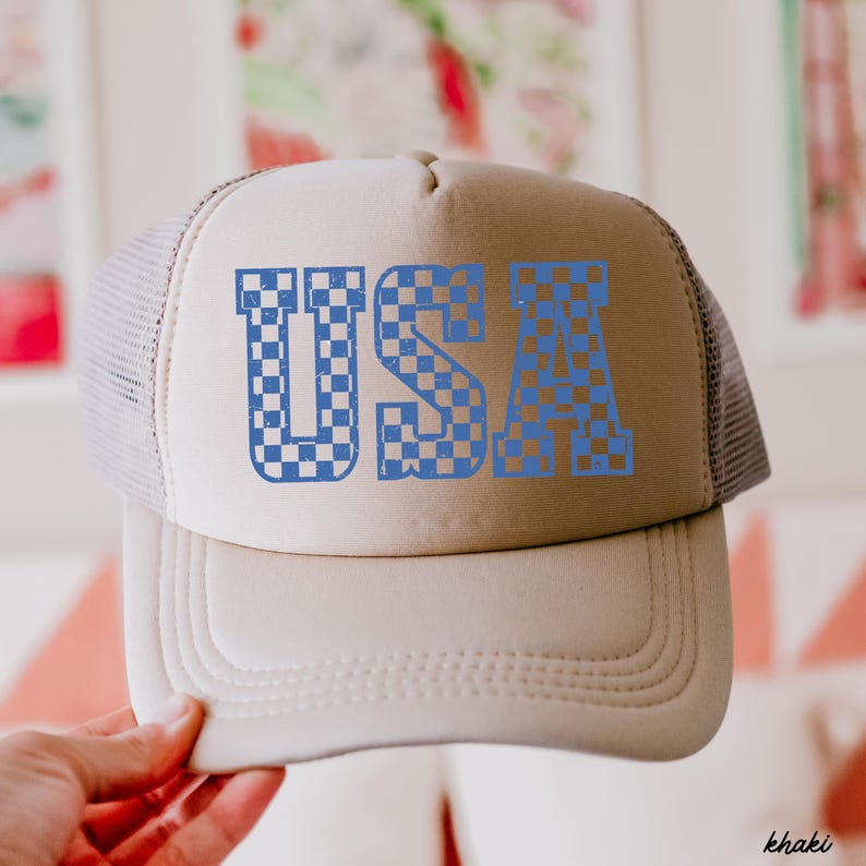 May include: A khaki trucker hat with a blue checkered "USA" graphic on the front.