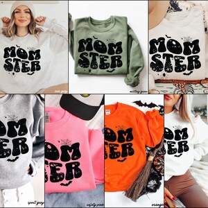 May include: A set of ten sweatshirts in various colors featuring a graphic print of the text "Momster" in a retro font with a spiderweb and bats. The sweatshirts are available in ash grey, military green, sport grey, safety pink, orange, and white.