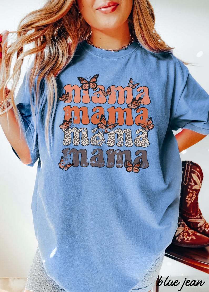 May include: A blue t-shirt with a graphic design that says "mama mama mama mama" in a retro font with butterflies and leopard print accents.