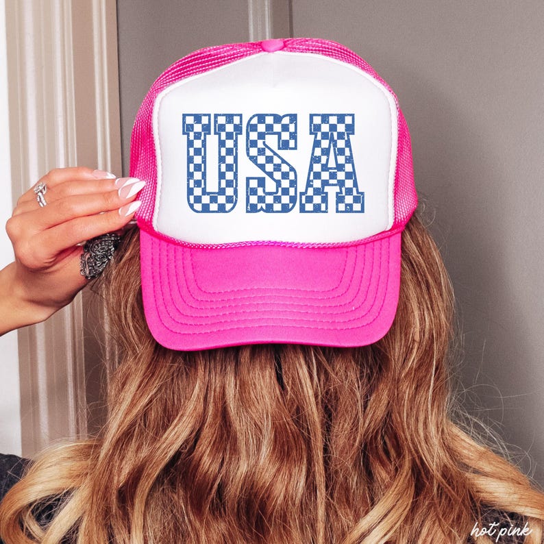 May include: A pink and white trucker hat with a blue and white checkered "USA" graphic.