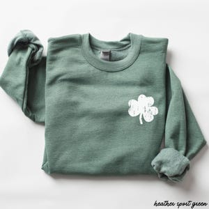 May include: A heather sport green sweatshirt with a white distressed shamrock design.