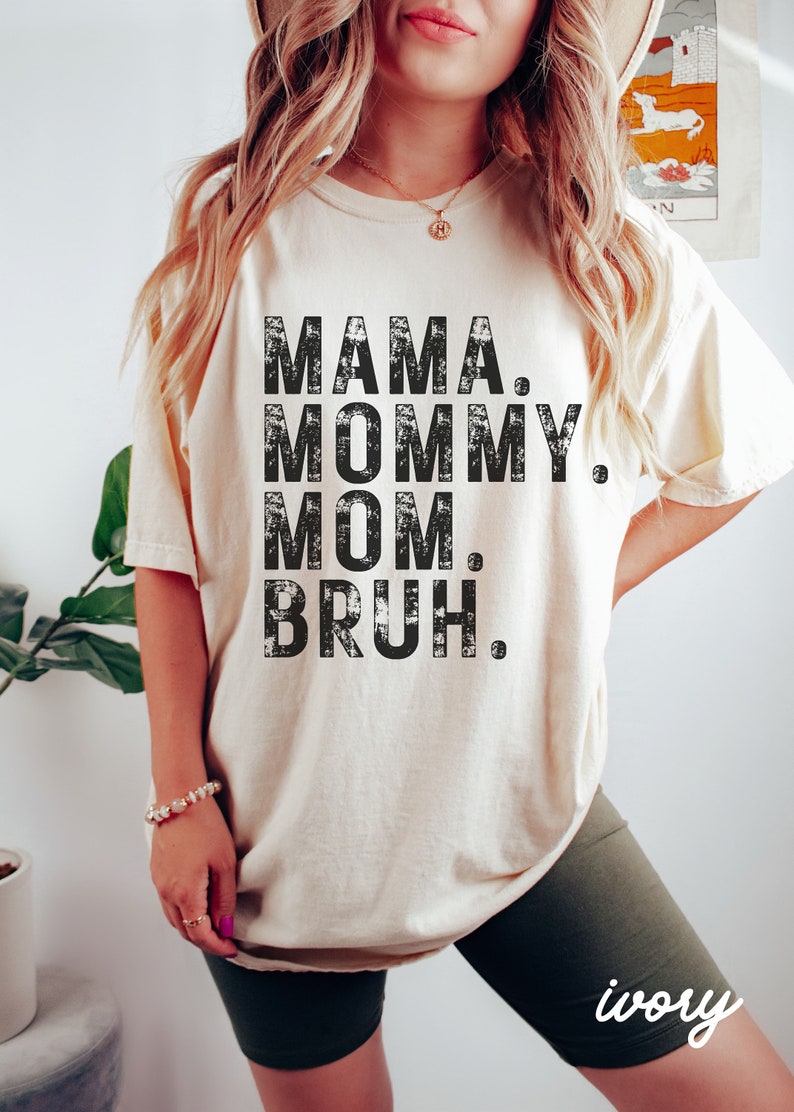 May include: A white t-shirt with black text that reads "MAMA. MOMMY. MOM. BRUH."