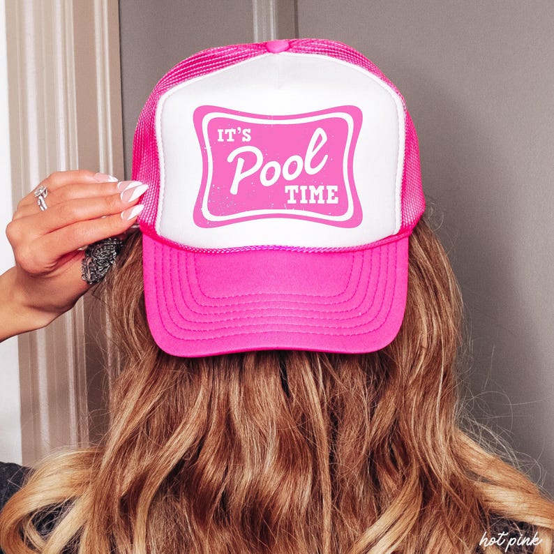 Może przedstawiać: Jaskrawor&oacute;żowa czapka typu trucker z białym panelem przednim. Na przednim panelu widnieje napis "IT'S Pool TIME" w kolorze r&oacute;żowym, w stylu retro. Czapka ma r&oacute;żowy daszek i siatkową tylną część.