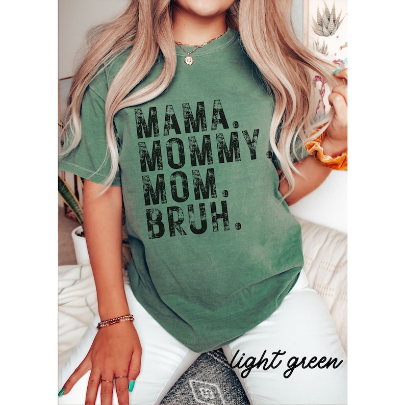 May include: A light green t-shirt with the text "MAMA. MOMMY. MOM. BRUH." printed in black.