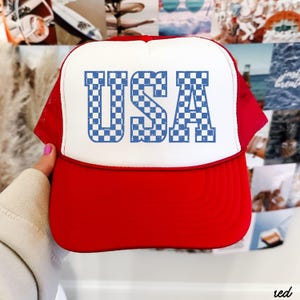 May include: Red and white trucker hat with a blue and white checkered "USA" graphic.