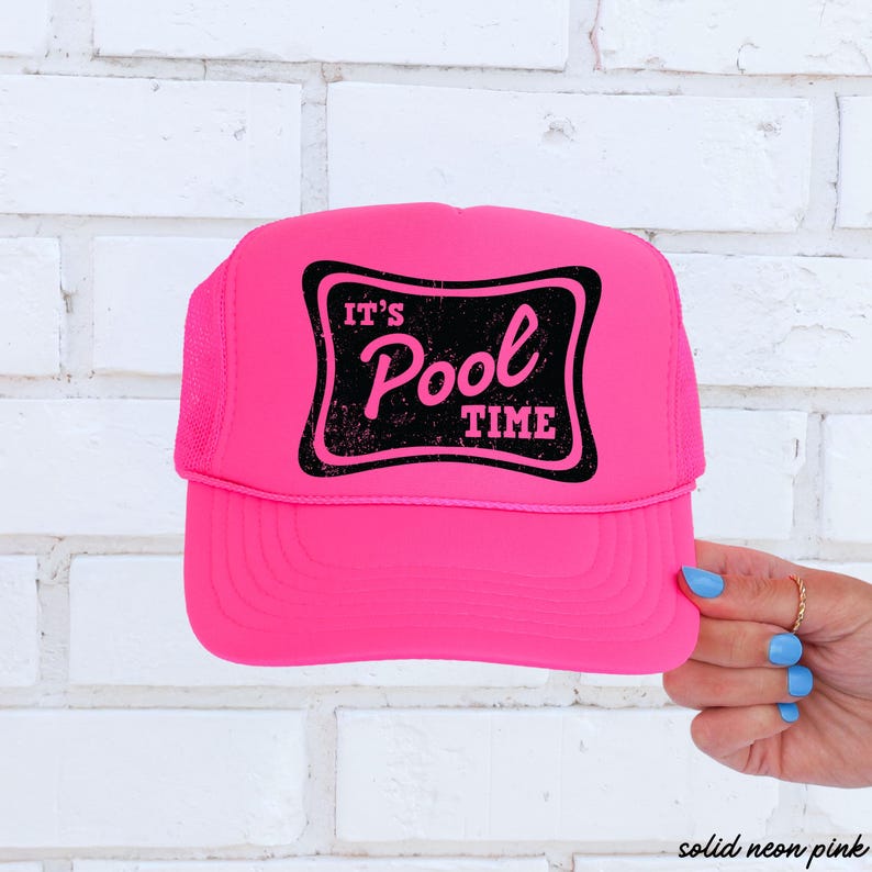 Może przedstawiać: Jasnor&oacute;żowa czapka typu trucker z czarną prostokątną naszywką z napisem "IT'S Pool TIME" w postarzanym kroju pisma. Czapka ma siatkowy tył i zakrzywiony daszek. Czapka jest trzymana przez dłoń z niebieskim lakierem do paznokci.