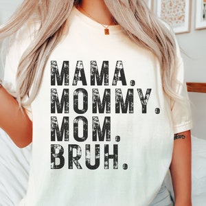 May include: A white t-shirt with a distressed black graphic that reads "Mama. Mommy. Mom. Bruh."
