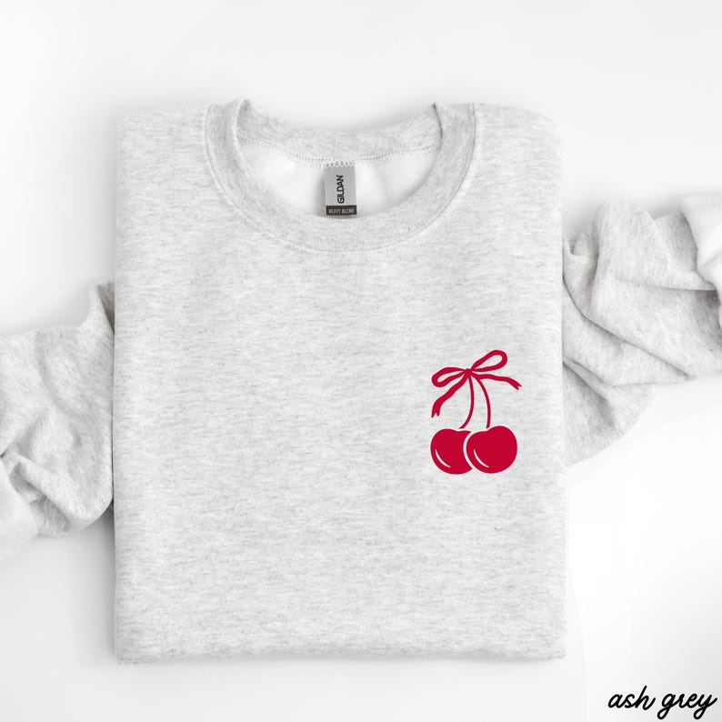 May include: Ash grey sweatshirt with a red cherry design on the front. The cherries have a red bow on top.