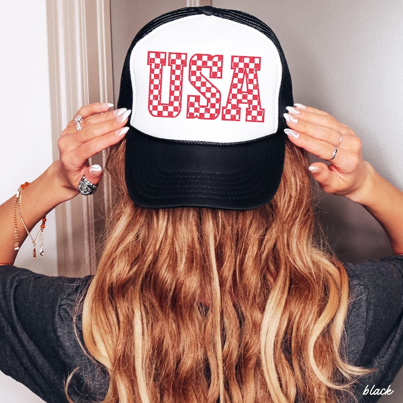 May include: Black and white trucker hat with a red and white checkered "USA" graphic on the front.