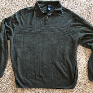 May include: A dark green long-sleeved sweater with a ribbed texture and a button-up collar.