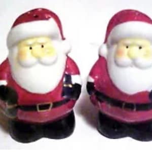 May include: A pair of ceramic salt and pepper shakers shaped like Santa Claus. The shakers are white with red hats, white beards, and black boots. They are holding a sack and a candy cane.