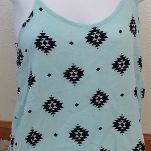 May include: A light blue sleeveless top with a black and white geometric pattern.