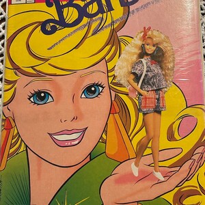 Może przedstawiać: Różowa i żółta okładka komiksu z kreskówkowym wizerunkiem Barbie z tekstem "FREE Barbie GIFT INSIDE" i "The Fabulous First Issue of Barbie".