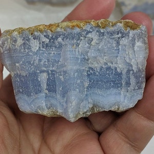 May include: A blue agate stone with white and brown banding. The stone is rough and has a natural, irregular shape.