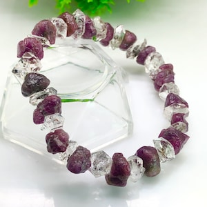 May include: A bracelet made of faceted, clear quartz and pink ruby crystals. The bracelet is approximately 15 cm in length.