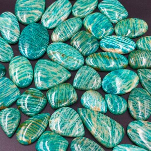 May include: A collection of green and white amazonite gemstone cabochons. The stones are smooth and polished, with a variety of shapes and sizes.
