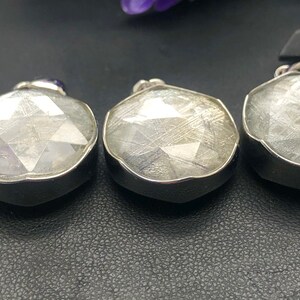May include: Three silver pendants with a clear, faceted, and textured stone. The stones have a white, gray, and silver color.