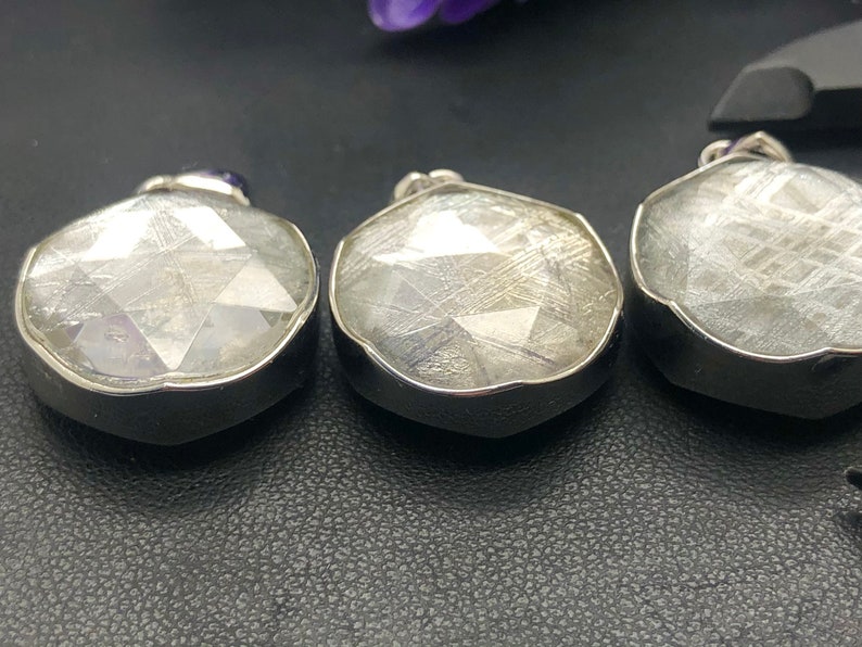 May include: Three silver pendants with a clear, faceted, and textured stone. The stones have a white, gray, and silver color.