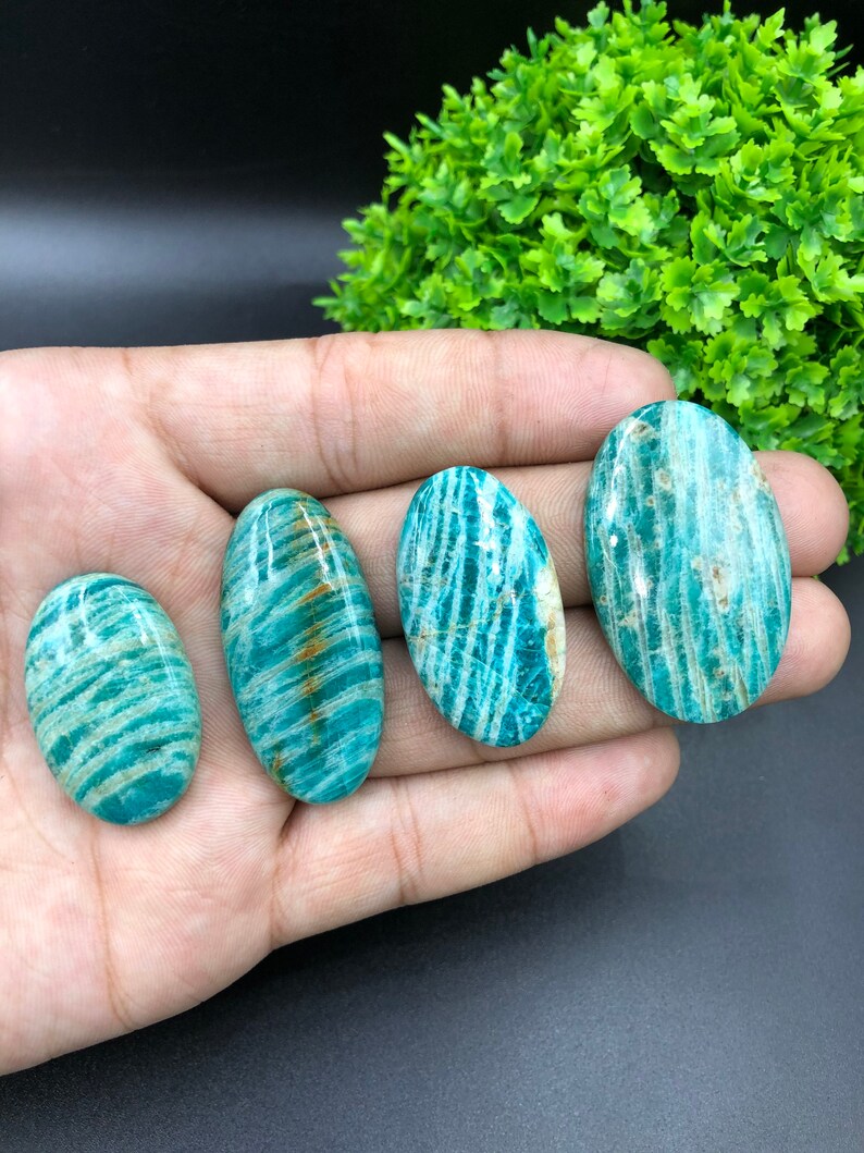 May include: Four oval-shaped green amazonite stones with white and brown stripes. The stones are smooth and polished.