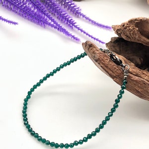 May include: A green crystal beaded bracelet with a silver clasp.