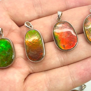 Puede incluir: Cuatro colgantes de forma ovalada con inserciones de piedras preciosas iridiscentes. Los colgantes son plateados y presentan una variedad de colores, incluyendo verde, rojo, naranja y amarillo.
