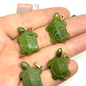 May include: Four green jade turtle pendants with gold-tone accents. The turtles are carved in a detailed design and have a smooth, polished finish.