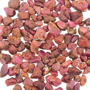 Op de afbeelding: Een grote verzameling ruwe, rode robijn edelstenen. De robijnen zijn van verschillende groottes en vormen en hebben een natuurlijke, onbewerkte afwerking.