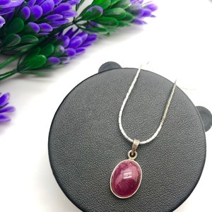 May include: A silver chain necklace with a pink oval gemstone pendant.