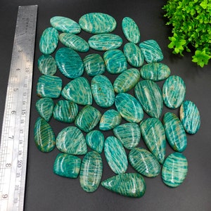 May include: A collection of 30 green amazonite cabochons, each with a unique striated pattern. The cabochons are various sizes and shapes, with a smooth, polished finish.