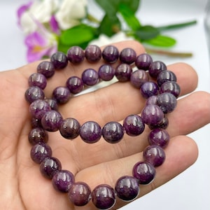 May include: A purple gemstone bracelet with round beads. The bracelet is made of natural stones and is a beautiful piece of jewelry.