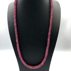 May include: A pink gemstone necklace made of round beads. The necklace is displayed on a black mannequin bust.