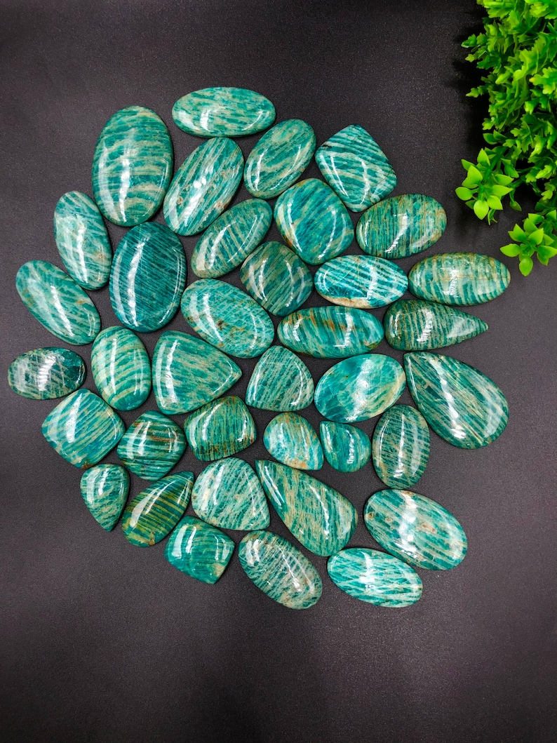 May include: A collection of 30 smooth, polished green amazonite stones with a striated pattern. The stones are oval and teardrop shaped.
