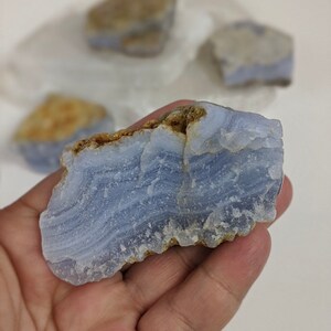 May include: A blue agate stone with white and brown banding. The stone is smooth and polished, and has a natural, irregular shape.