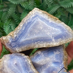 May include: Three blue agate stones with white and brown banding. The stones are stacked on top of each other. The top stone has the text "LapisBK" written on it.