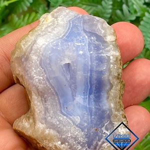 May include: A blue agate geode with a white and brown exterior. The geode is partially cut open, revealing the blue agate inside. The geode is approximately 7.5 cm in diameter.