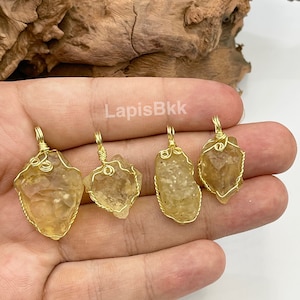 Puede incluir: Cuatro colgantes de cristal de citrino amarillo envueltos en alambre dorado. Los colgantes son todos de diferentes formas y tamaños.