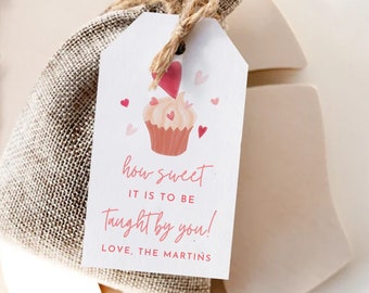 May include: A white gift tag with a pink cupcake illustration and pink hearts. The text on the tag reads "how sweet it is to be taught by you! Love, The Martins".