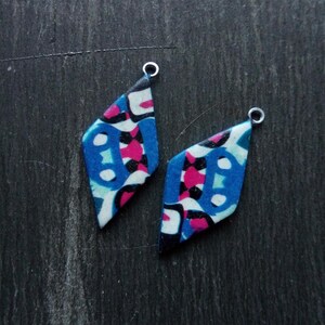 May include: Two diamond-shaped earrings with a colorful abstract pattern in shades of blue, pink, black, and white. The earrings have silver jump rings.