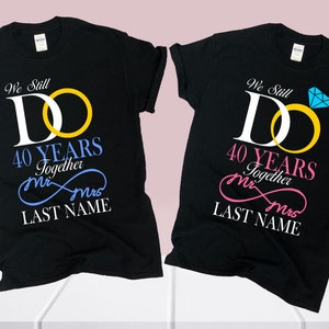 May include: Two black t-shirts with a graphic design of two interlocking rings and the text "We Still Do 40 Years Together Mr & Mrs LAST NAME".