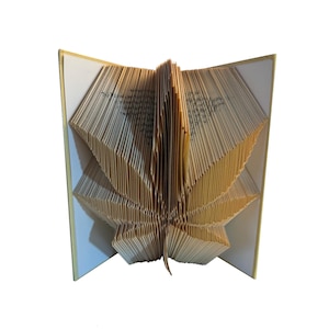 May include: A book art sculpture of a leaf, folded from the pages of a book. The pages are folded into a three-dimensional shape, creating a realistic representation of a leaf.