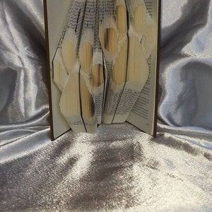 May include: A book with pages folded into the shape of a paw print. The book is brown and has a white background. The paw print is made of white paper.
