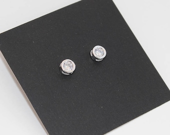 May include: A pair of silver stud earrings with clear round cubic zirconia stones.