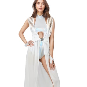 May include: A futuristic white outfit featuring a high-neck bodysuit, a long sheer skirt with a high slit, and a structured top with cut-out details. The outfit includes matching gloves and a belt with a silver buckle. The model is wearing white strappy heels.