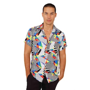 以下が含まれることがあります： カラフルな幾何学模様の半袖ボタンダウンシャツ。シャツは白地に黒、赤、黄、青、緑の幾何学模様が施されています。
