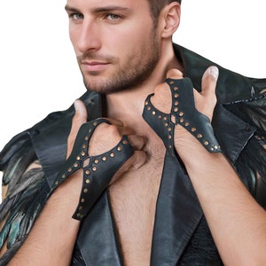 May include: A man wearing a black leather jacket with a feather trim and black leather fingerless gloves with gold studs.