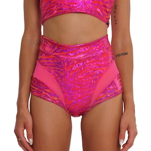 Peut inclure: Short en jean taille haute rose et rouge à imprimé zèbre et empiècements en mesh. Le short a une jambe haute et une taille basse.