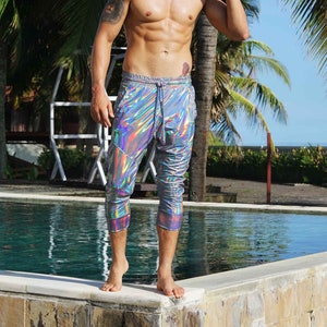 Puede incluir: Una persona con pantalones plateados iridiscentes de pie junto a una piscina.