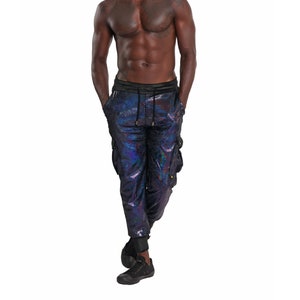 May include: A man wearing black cargo pants with a iridescent blue and purple pattern. The pants have a drawstring waist and cargo pockets.