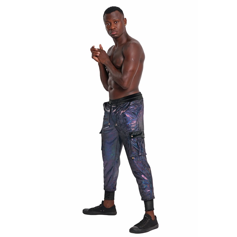 May include: A man wearing black cargo pants with a iridescent finish. The pants have a drawstring waist and a zippered pocket on the right leg.